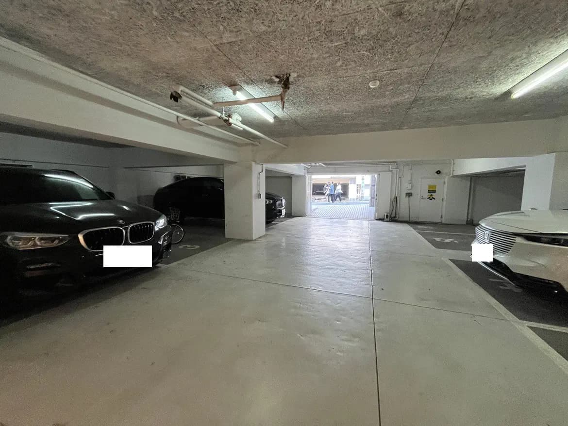 - 駐車場の内部、複数の車が駐車されている様子、明るい照明と広々としたスペースが特徴の風景
