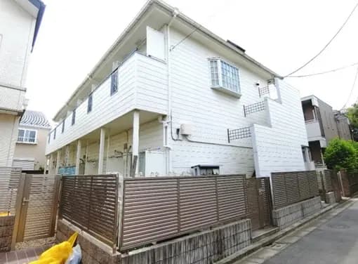 - 白い外壁の2階建て住宅、バルコニー付きで、フェンスに囲まれた周囲の様子