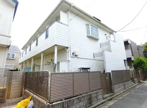 - 白い外壁の2階建て住宅、バルコニー付きで、フェンスに囲まれた周囲の様子