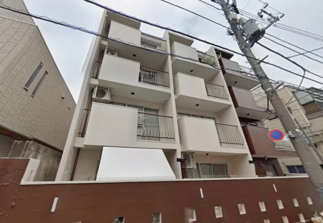 - シンプルでモダンなデザインのマンション外観、バルコニーと窓があり、周囲に電柱が立つ街並み