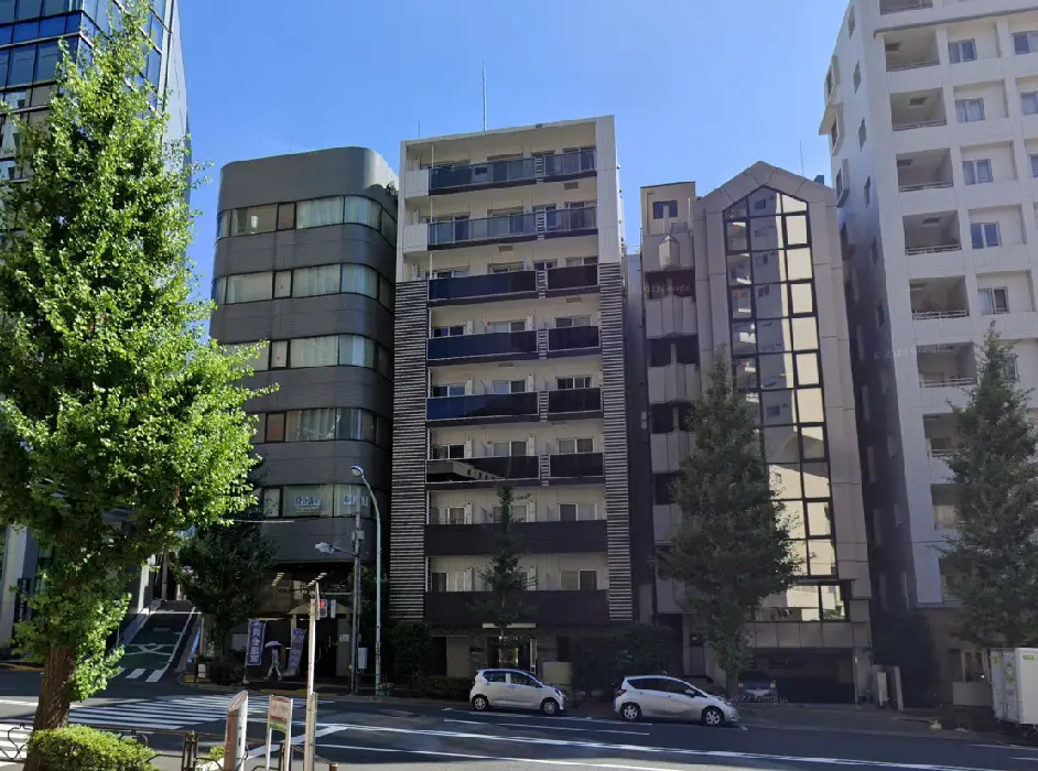 - 近代的なビル群が立ち並ぶ街並み、青空の下で緑の樹木が並ぶ通りの風景