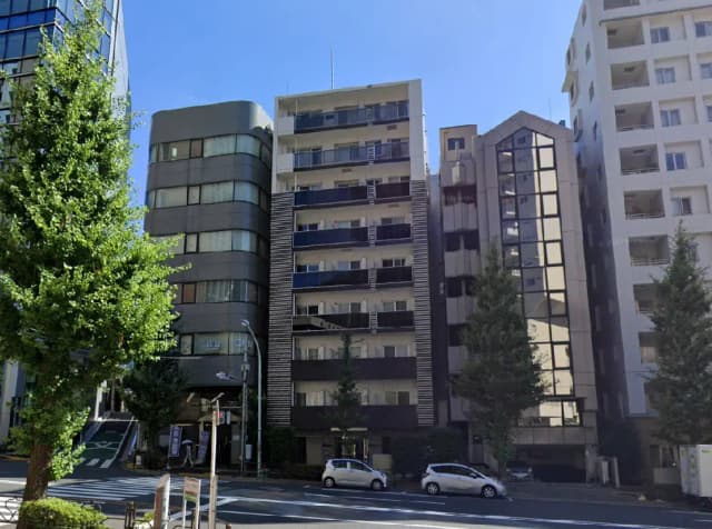 - 近代的なビル群が立ち並ぶ街並み、青空の下で緑の樹木が並ぶ通りの風景
