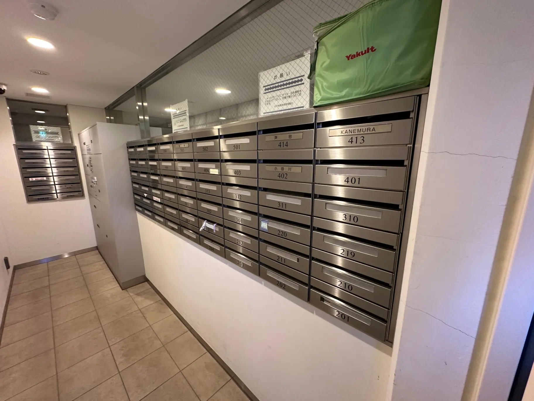 マンションの室内郵便受けとYakultの配達バッグが置かれている廊下