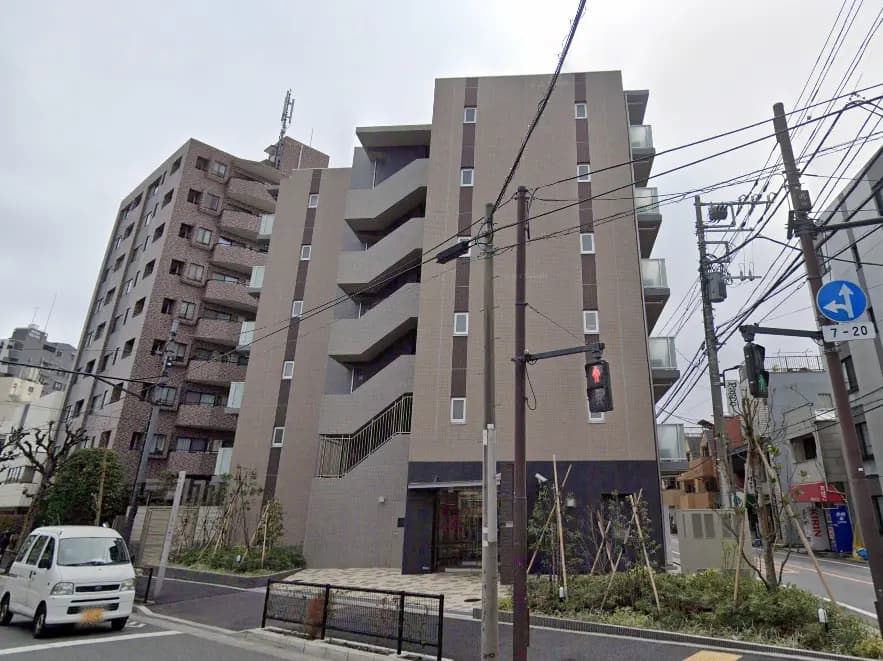 - 現代的なデザインのアパートメントビル、エントランスに階段があり、周囲には緑と街灯のある都市景観
