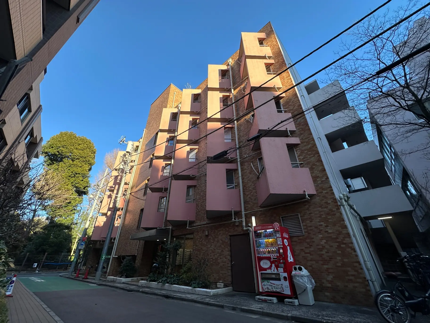 都市のアパート建物と自動販売機、晴れた日の明るい青空