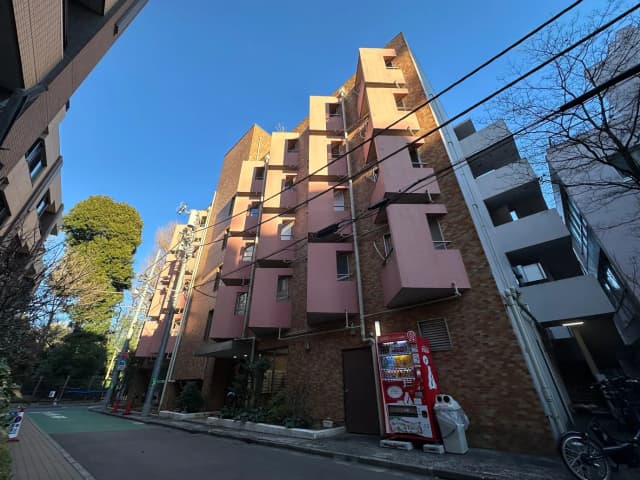 都市のアパート建物と自動販売機、晴れた日の明るい青空