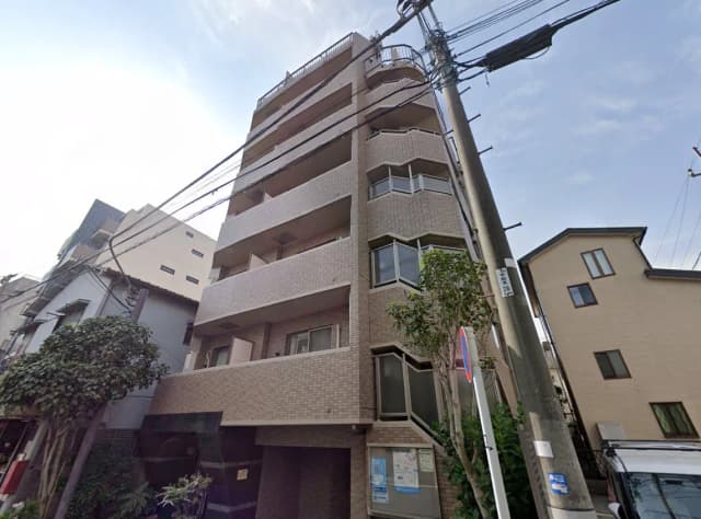 - 都市型の集合住宅、モダンな外観と複数のバルコニーを備えた5階建ての建物、周囲には緑豊かな植栽があり、住宅街に位置する景観