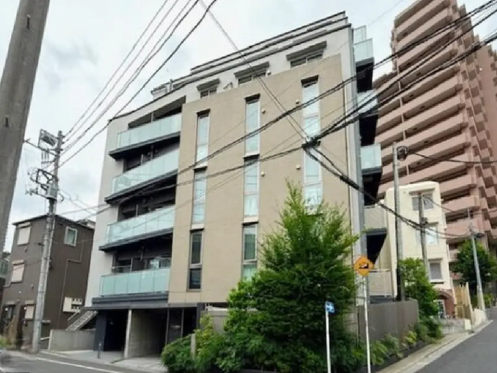 - モダンな外観のマンション、バルコニー付き、周囲に電柱や緑がある街並みの景色