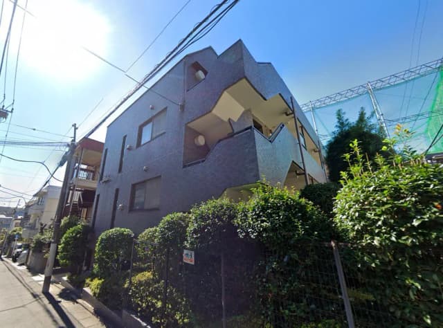- 現代的なデザインのアパートメントの外観、緑豊かな植栽と青空を背景にした建物の写真