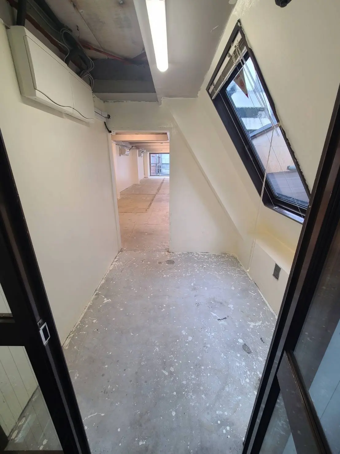 リノベーション前のオフィス空間、天井が開いている部屋、窓側には床に塗料がこぼれている