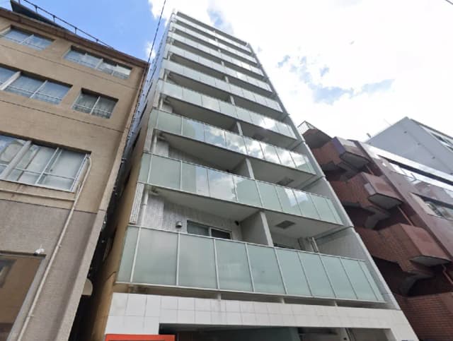 - コンテンポラリーデザインの中層ビル、ガラスバルコニーとシンプルな外観、周囲には異なる建物が立ち並んでいる景観