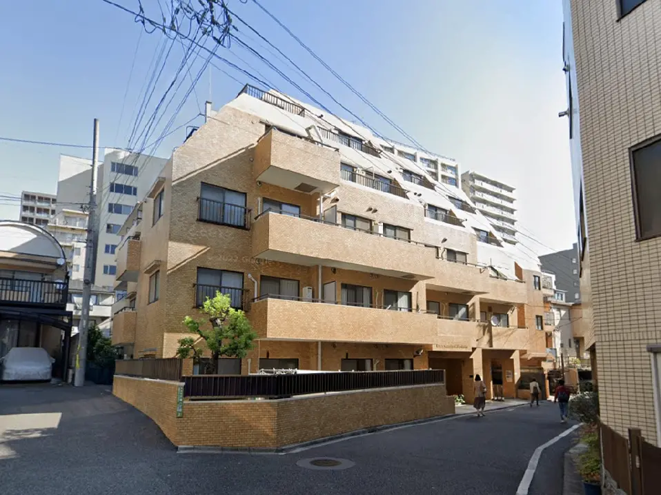 - モダンなデザインのアパートメントビル、ブロック状の外観、周囲の街並みとの調和、通りを歩く人々と緑の植栽