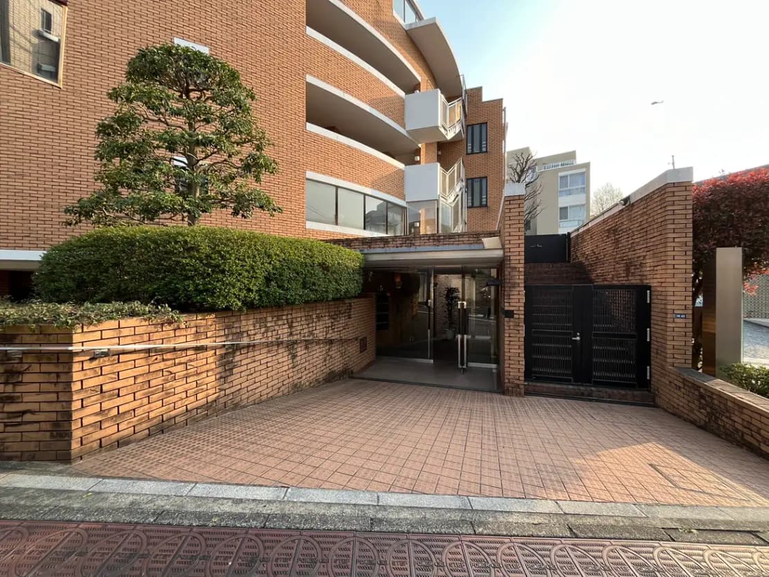 - モダンな住宅のエントランス風景、レンガ造りの壁と手入れされた植栽、広々としたアプローチがあるデザイン
