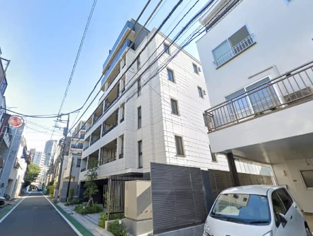 - モダンな外観の集合住宅、周囲に街路樹と電線が見える静かな通りの風景