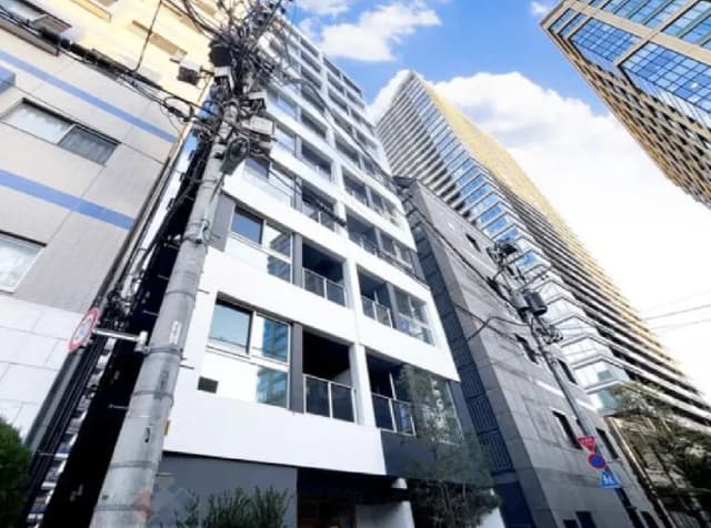 - モダンなデザインの高層ビルが並ぶ都市の景観、青空に映える白と黒のファサード、電柱と電線が交差する風景