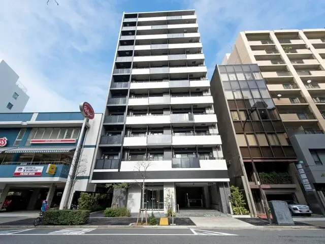 - 現代的なデザインのマンション外観、ガラスバルコニーと周囲の高層ビルが並ぶ街並み