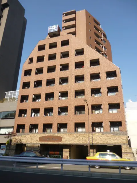 - モダンなデザインのレンガ造りのビル、整然とした窓配置と周囲の都市景観を背景にした外観
