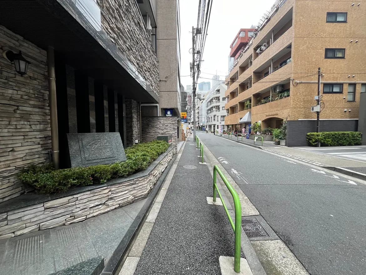 - 都会的な雰囲気の住宅街、レンガ造りのアパートと石材のファサード、街路樹が並ぶ歩道の様子
