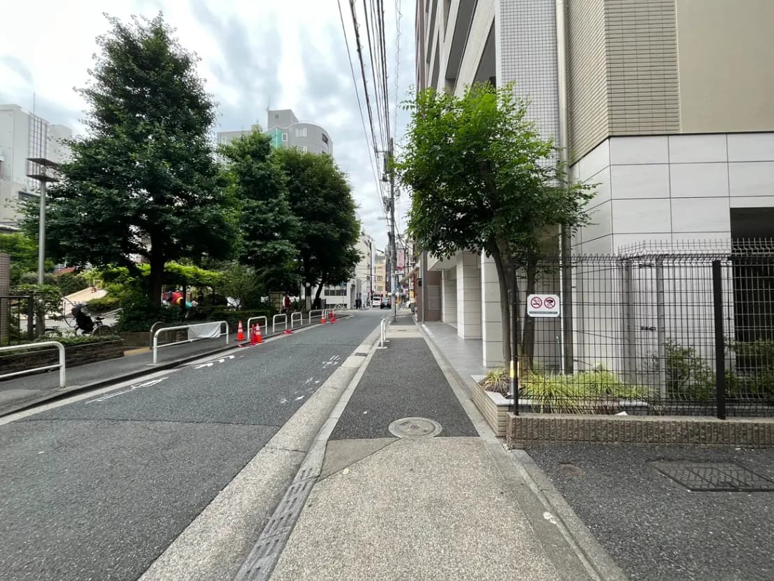 - 緑豊かな街並みと住宅街、歩道に並ぶ木々と交通標識、静かな通りの風景