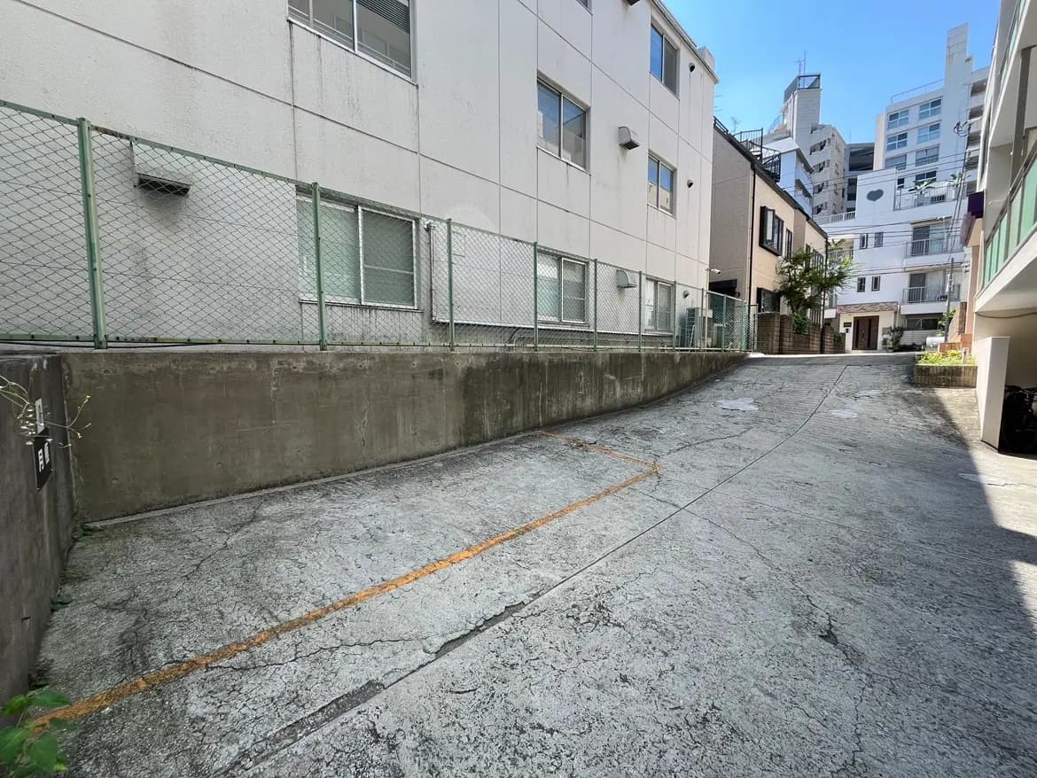 - コンクリートの傾斜道と周囲のビル、フェンスで囲まれた都市の風景、青空が広がる背景の写真
