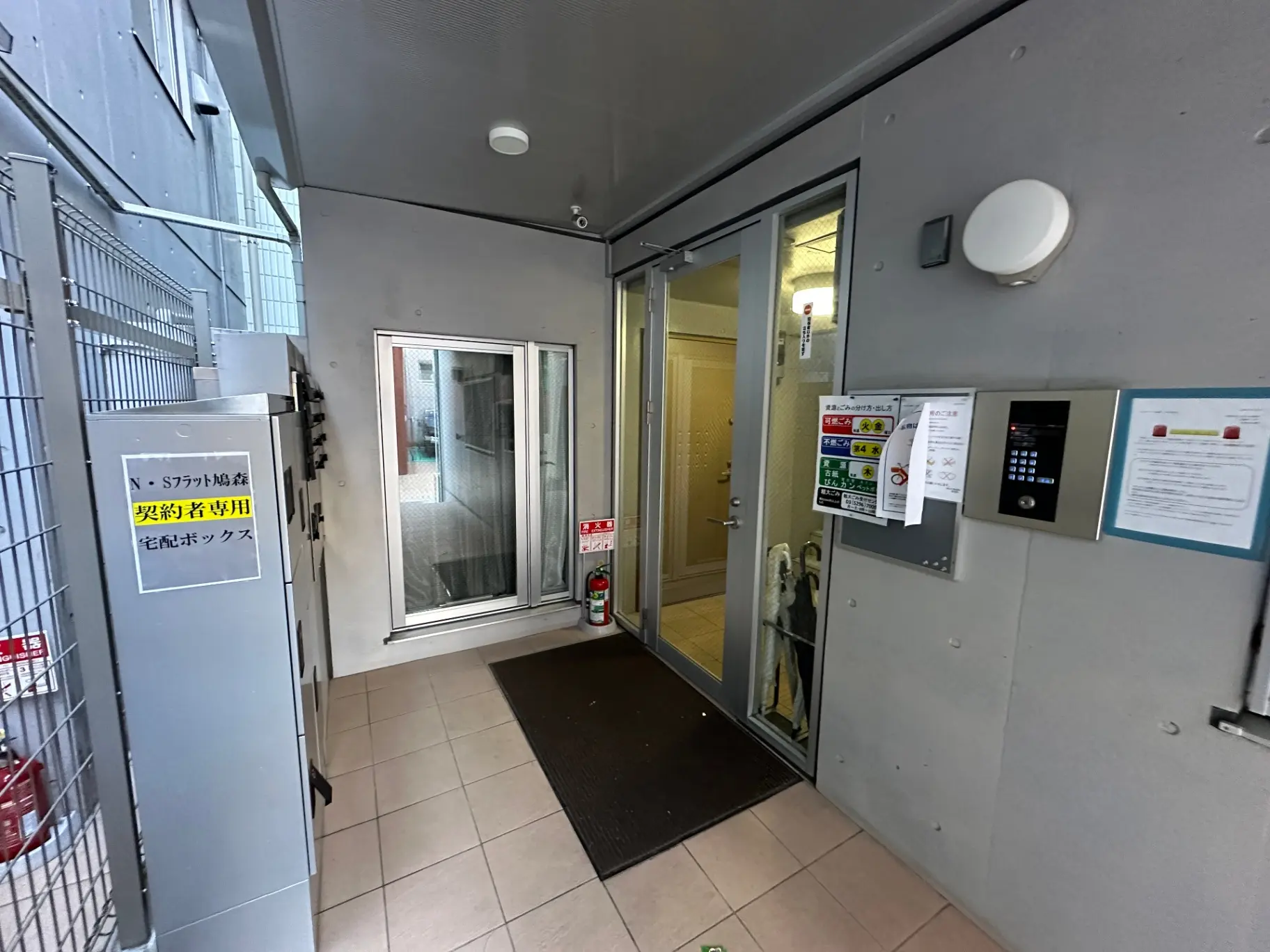 オフィスビルの入口エリア、セキュリティシステムと案内看板が設置されている玄関ホール