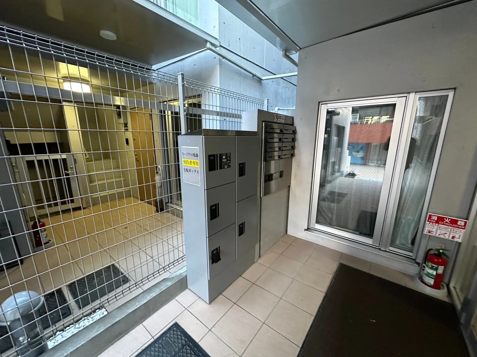 マンションのエントランスホール、宅配ボックスと防犯カメラの看板が見えるセキュリティ対策