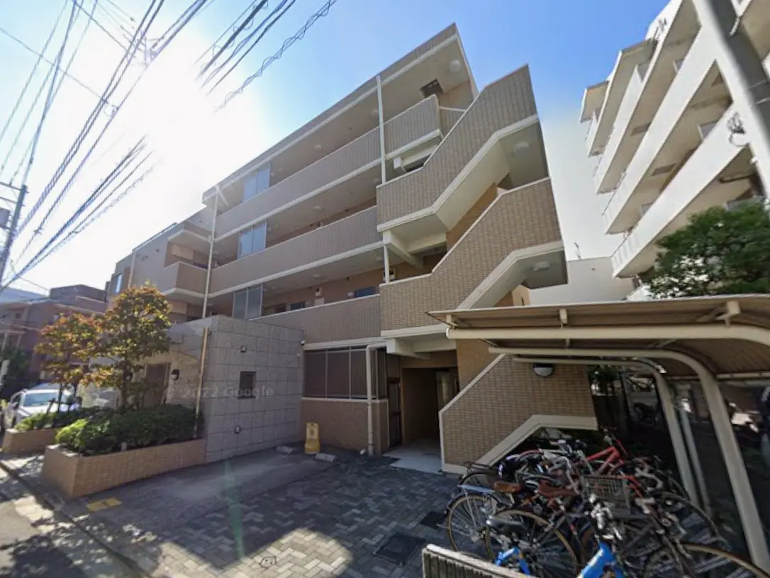 - 日差しが差し込む現代的なアパートの外観、バルコニーや自転車置き場が整った周辺環境