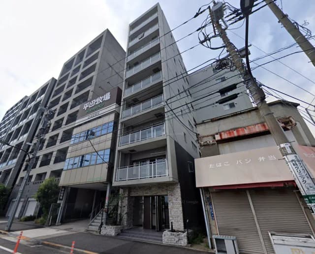 - モダンな外観の集合住宅「平田牧場」、近くに電柱と商店があり、周囲の環境が見える街並みの風景