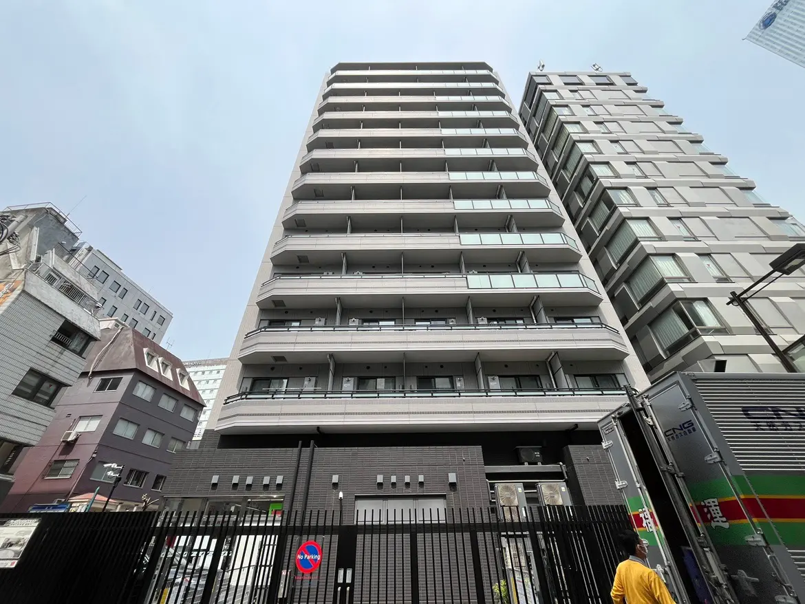 - 都市の中に立つモダンな高層マンション、バルコニー付きの管状デザインと周囲の建物とのコントラスト