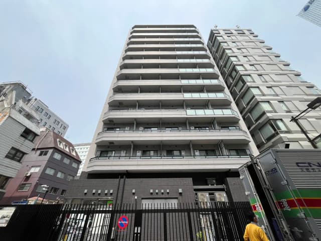 - 都市の中に立つモダンな高層マンション、バルコニー付きの管状デザインと周囲の建物とのコントラスト