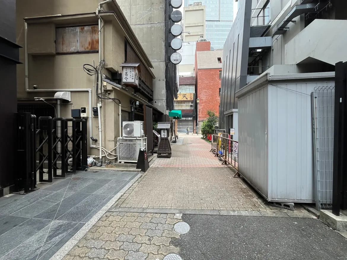 - 都市の狭い通り、古い建物と現代的な構造物が混在し、飲食店が並ぶ風景