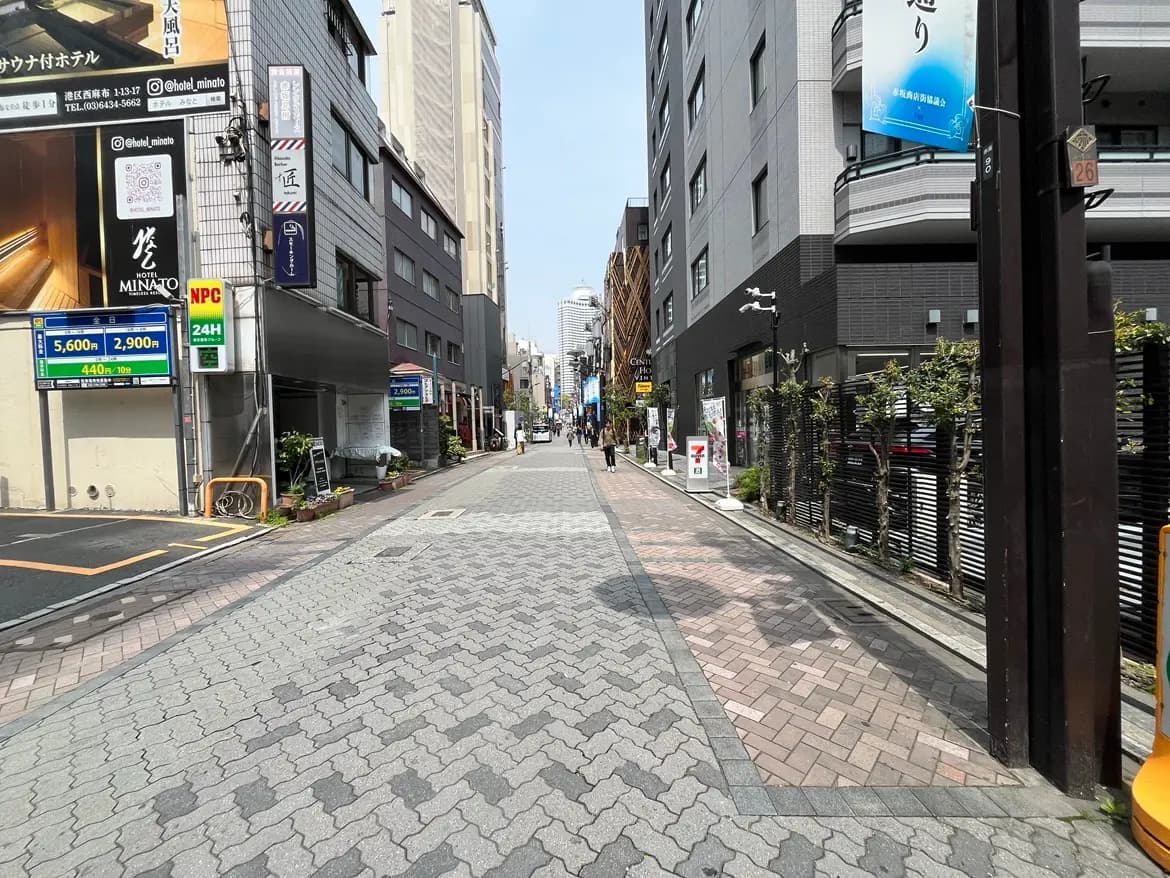 - 都市の中の静かな通り、両側に店舗やビルが並ぶ石畳の道と緑の植栽がある風景