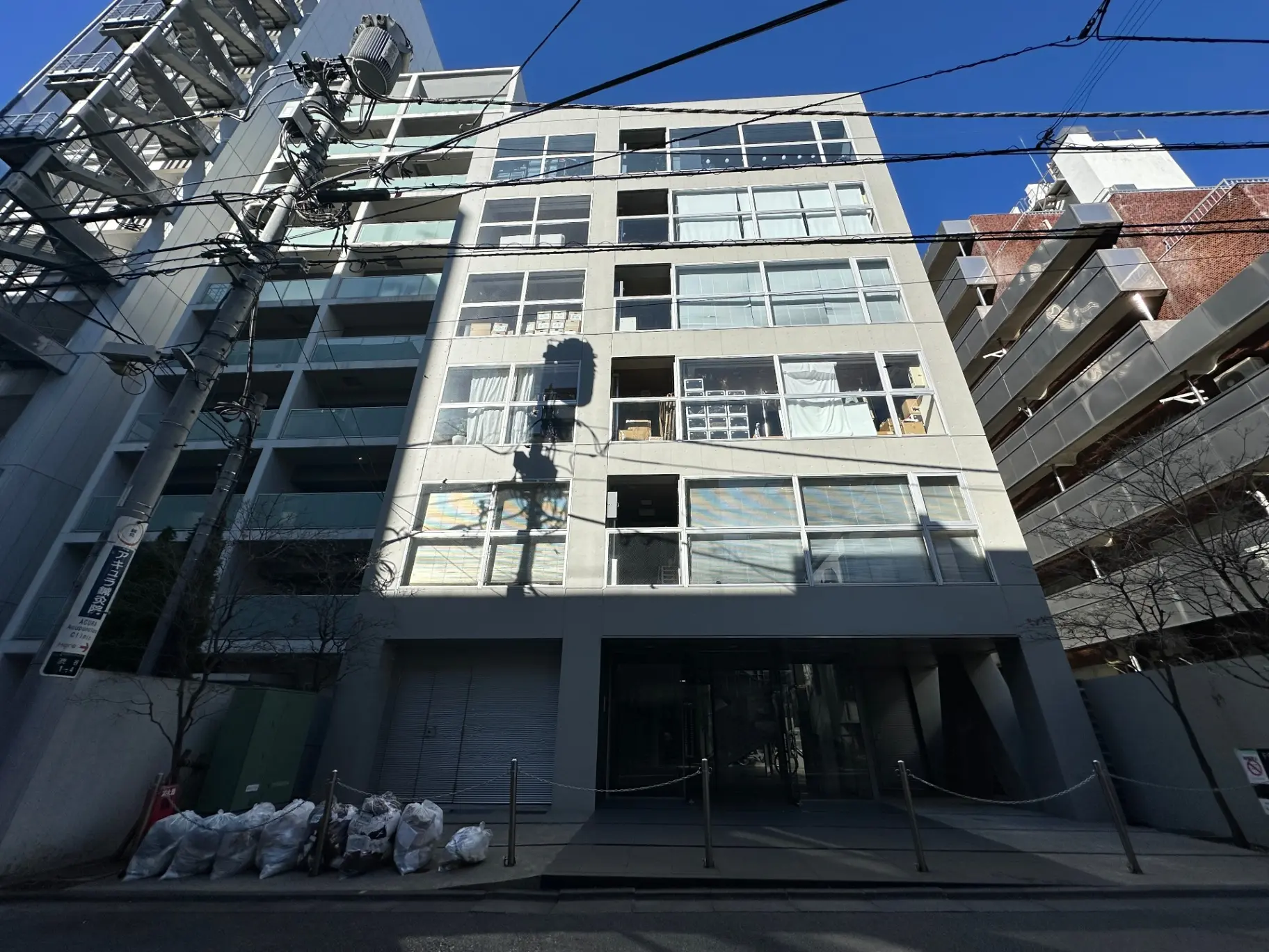現代的な外観の都市型マンション、ガラス窓とコンクリートの壁、明るい日差しの中の建築デザイン