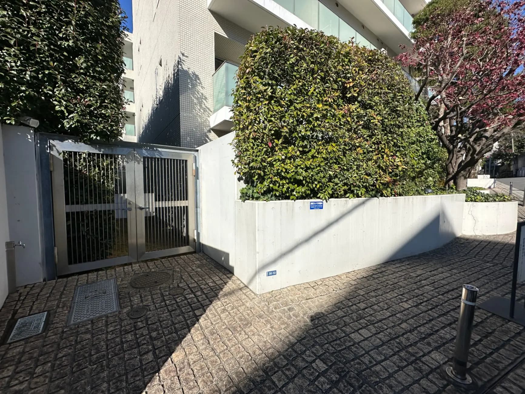 都市の門扉とコンクリートの壁、樹木と青空が見える外観