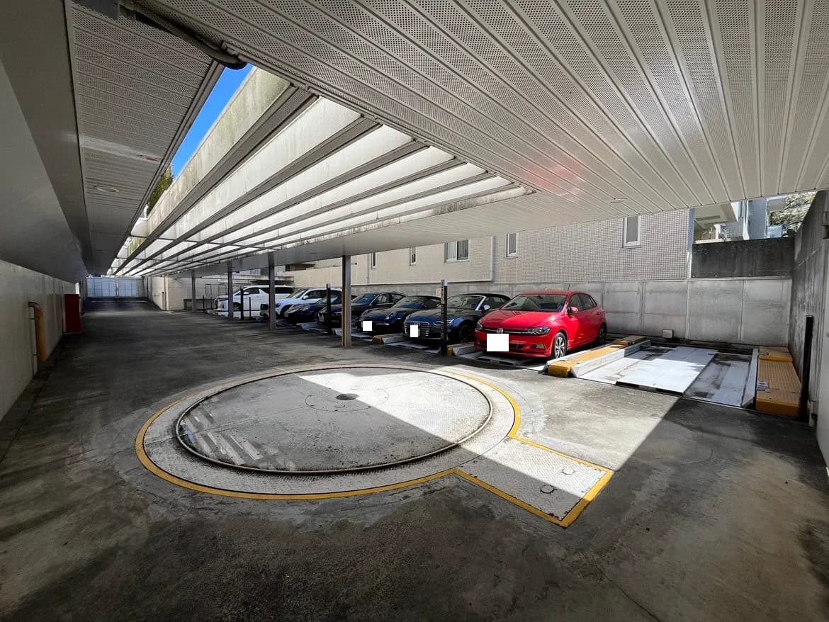 - 屋根付きの駐車場、白い車と赤い車が並ぶガレージエリア、回転位置決め装置のあるスペース