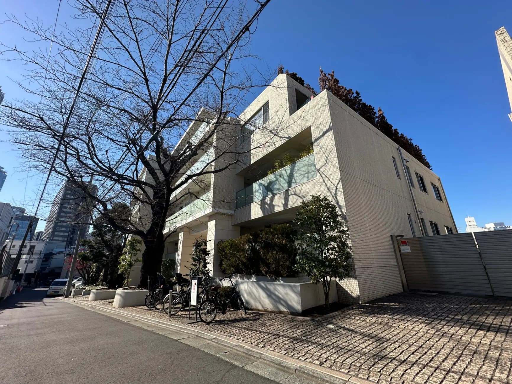 現代的な外観の都市型マンション、日差しが差し込む住宅街の風景