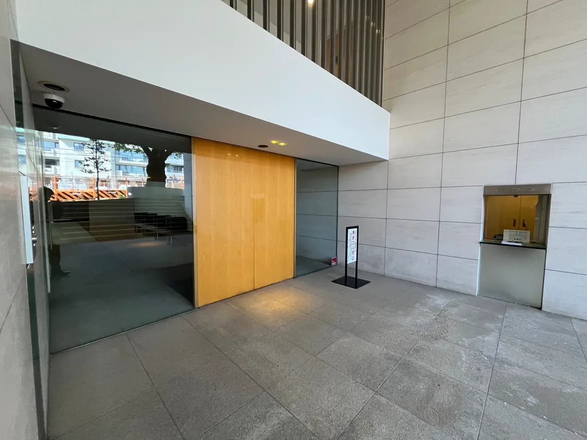 - 現代的な入口のデザイン、木製のドアとガラスの壁、シンプルな受付カウンターがある広々としたエントランスホール
