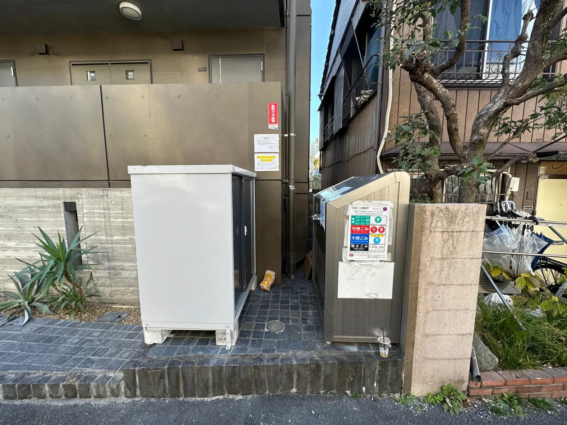路地に置かれた冷蔵庫とゴミ箱、リサイクルの案内ステッカーが貼られた都市環境
