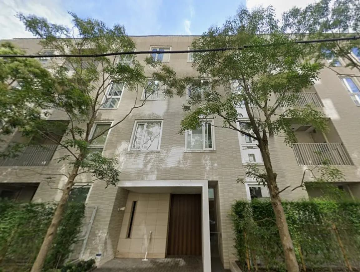 モダンな外観の都市型マンション、緑豊かな樹木と洗練されたエントランス