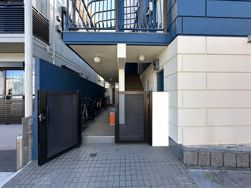 建物の入口付近で多数の自転車が停められている都市のアパート、屋外に設置された階段と青い壁