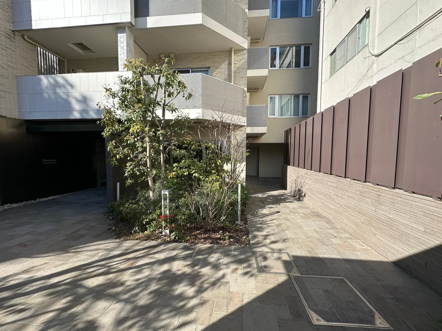 モダンなマンションのエントランス、日当たり良好、緑豊かな植栽がある外観