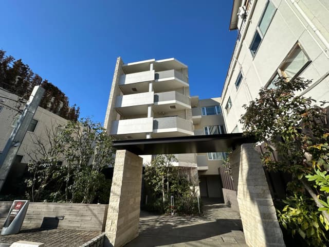 現代的なマンションの外観、晴れた日に撮影されたクリアな青空と周囲の緑が映える景観