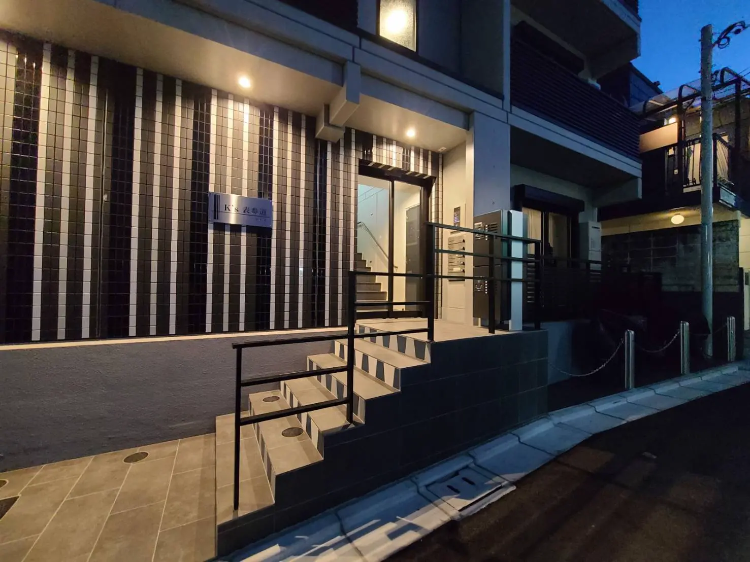 夕暮れ時のモダンな外観の住宅、エントランスには照明があり、エレガントな雰囲気を演出