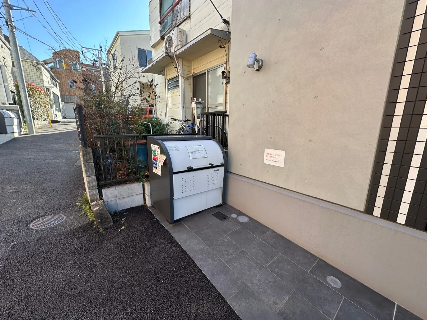 日本の住宅街にあるゴミステーション、分別指示のあるゴミ箱とアパートメント、晴れた日の都市風景