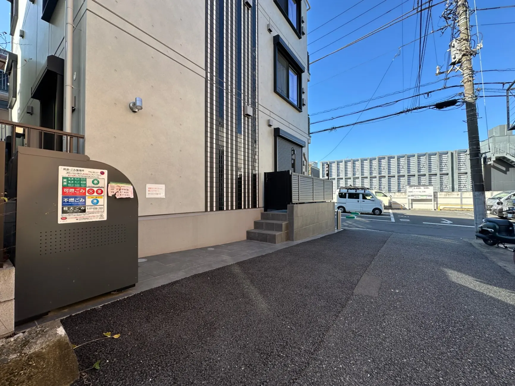都市の風景、歩道に設置されたごみ収集ボックス、近代的な建物の外観、晴れた日の青空