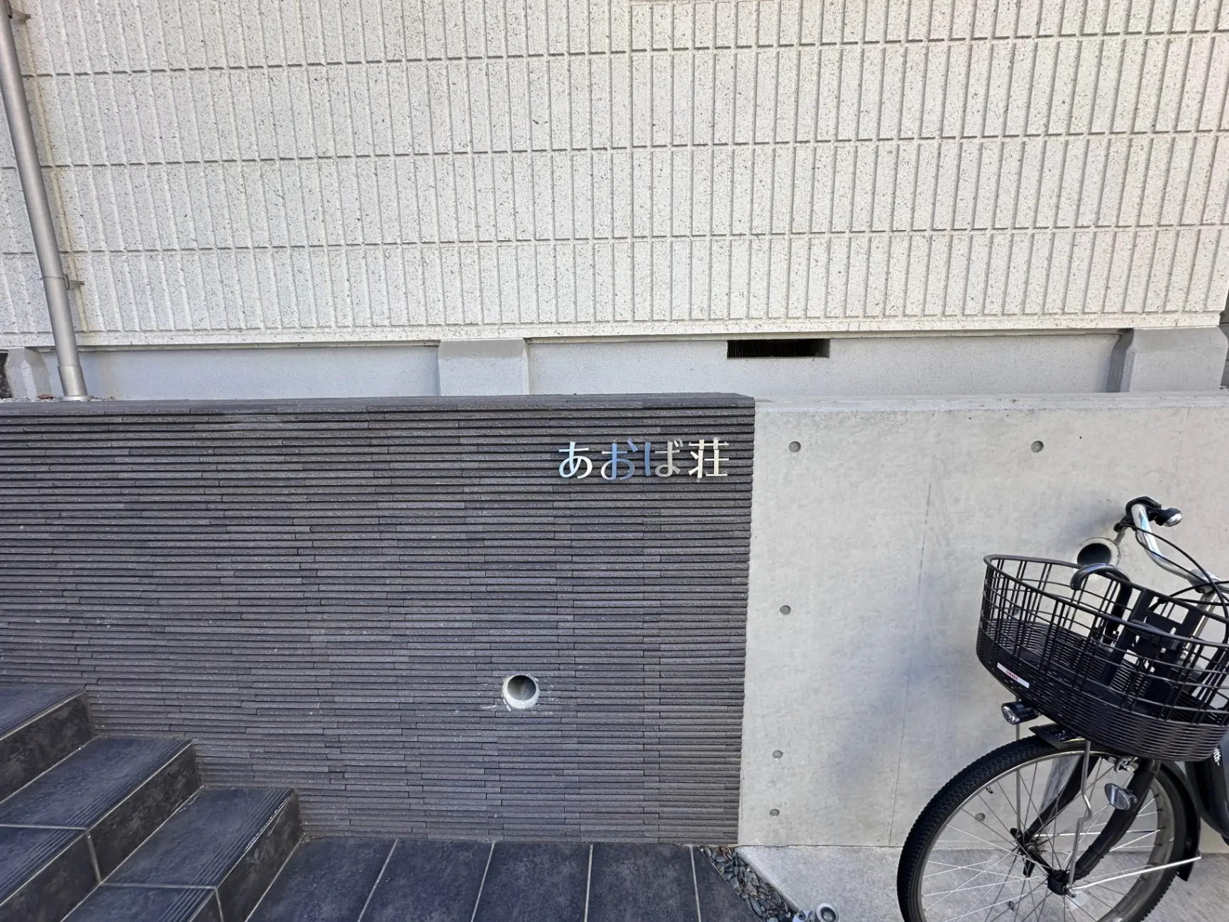 建物の入口にある階段と「あたままわり」の標識、自転車が置かれた都市の風景