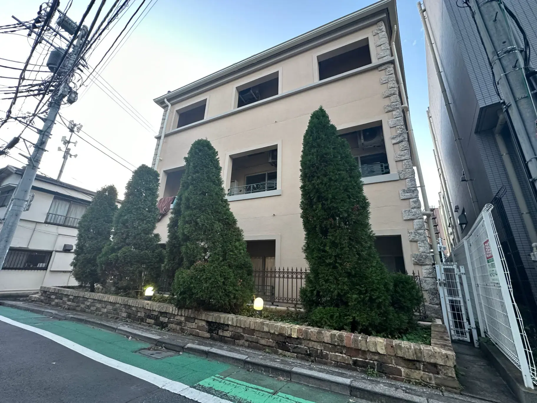 落ち着いた色合いの外観を持つ、樹木に囲まれたアパートビル