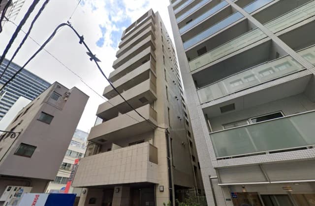 - 高層マンションの外観、隣接するビルと電線が映る都市風景の一部