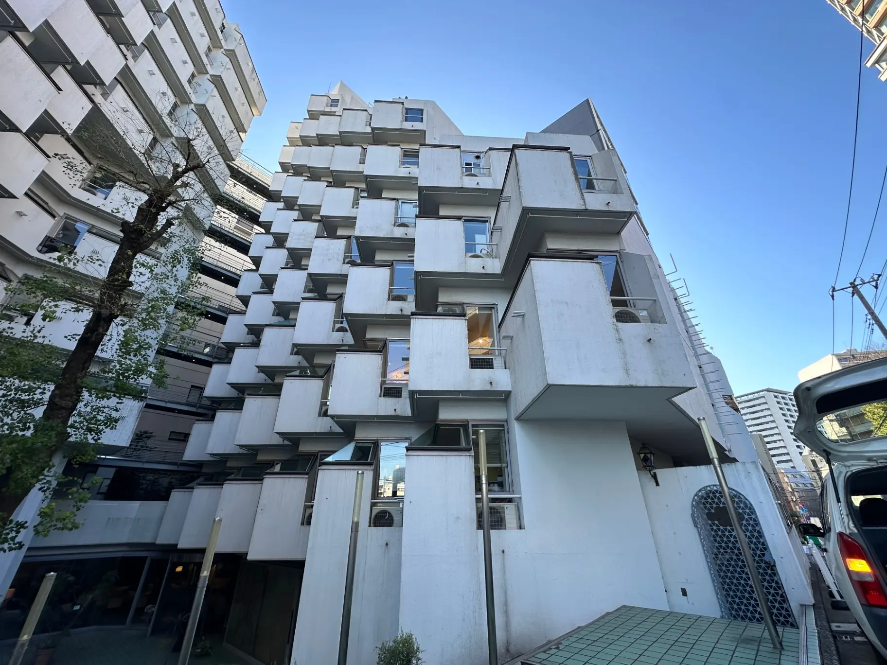 独特な構造を持つモダンな集合住宅、都市環境に溶け込む白いファサード、青空の下での建築美