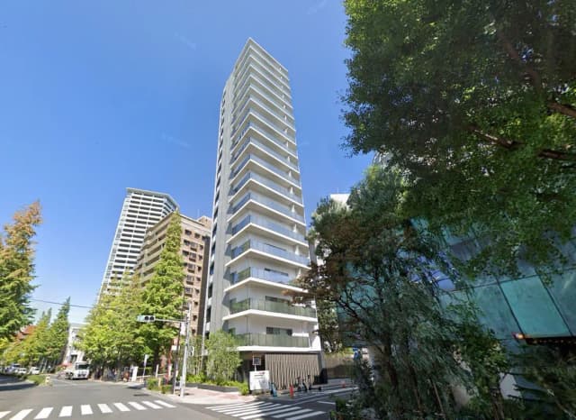 都市の交差点にある高層マンションと緑豊かな樹木、晴れた日の青空